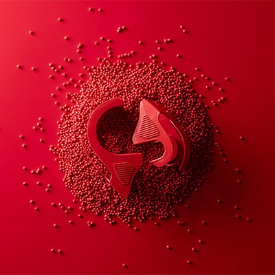 Distributore rosso di nastro da imballo Scotch™ su sfondo rosso di perline rosse di plastica riciclata