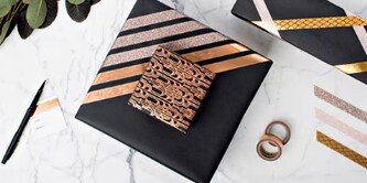 Combinare regali attaccando un regalo più piccolo a uno più grande utilizzando il Nastro biadesivo Scotch®
