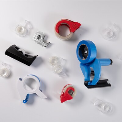 Diversi dispenser di nastro adesivo su sfondo bianco.