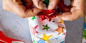 Utilizzare carta da imballaggio stellata e completare l'aspetto dell'impacchettamento regalo con una stella di nastro in cima
