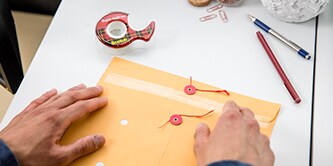 Uomo che sigilla una busta con il nastro Super-Hold Tape Scotch®
