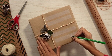 Creare etichette regalo utilizzando il Nastro adesivo Scotch® Magic™ su un regalo impacchettato con carta da imballo semplice
