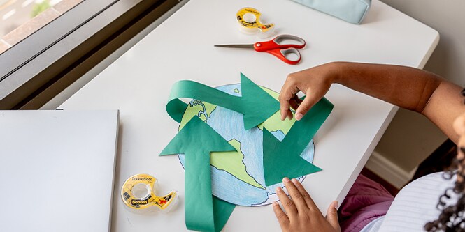 Ragazza che crea una mappa del mondo fatta di carta con materiali del marchio Scotch™
