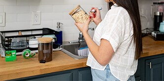 Donna che crea etichette fai da te con il nastro adesivo Scotch® Magic™ e le applica su contenitori per alimenti
