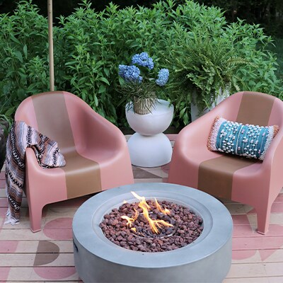 Un patio esterno con una terrazza dipinta e un moderno braciere circolare al centro.